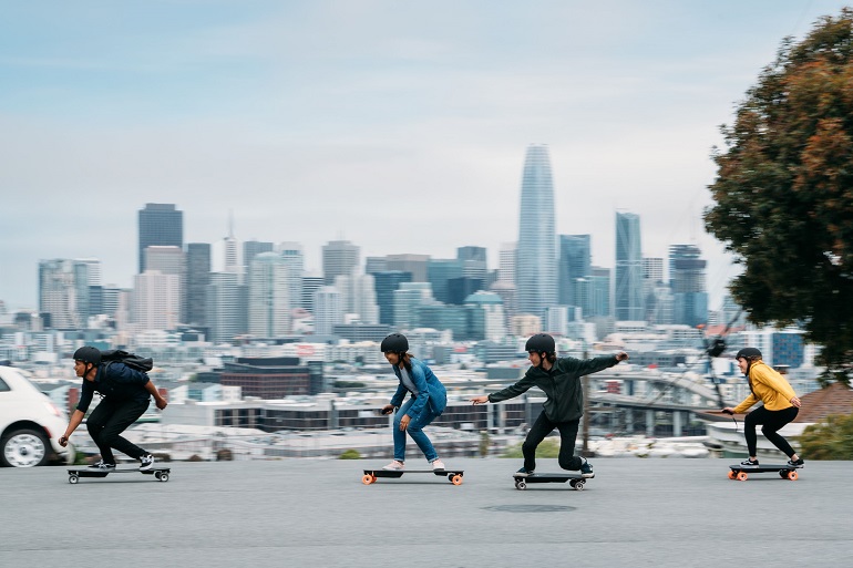 group of people riding electric skateboards with helmets 