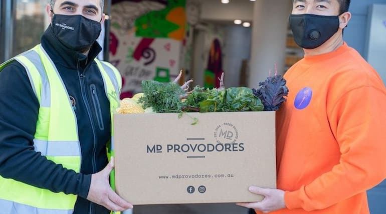 Two men delivers food from MD Provodores in cartoon box