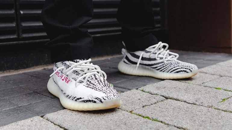 person wearing adidas yeezy 350 in zebra colours
