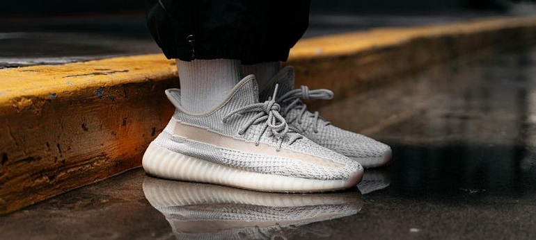 person wearing adidas yeezy 350 v2 standing on wet ground