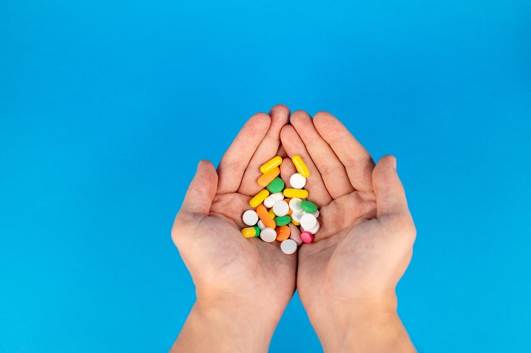 picture of hand holding pills on blue background