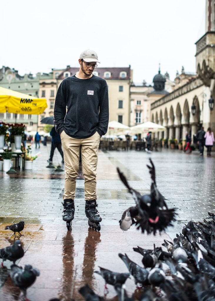 picture of a person standing beside birds on the plaza in his inline skates