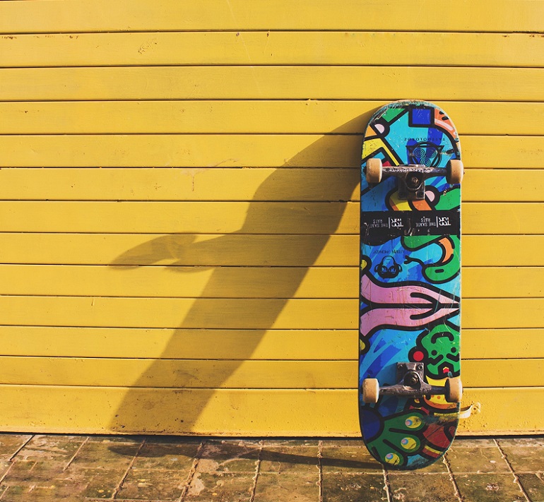 picture of a colorful skateboard on a yellow wall background 