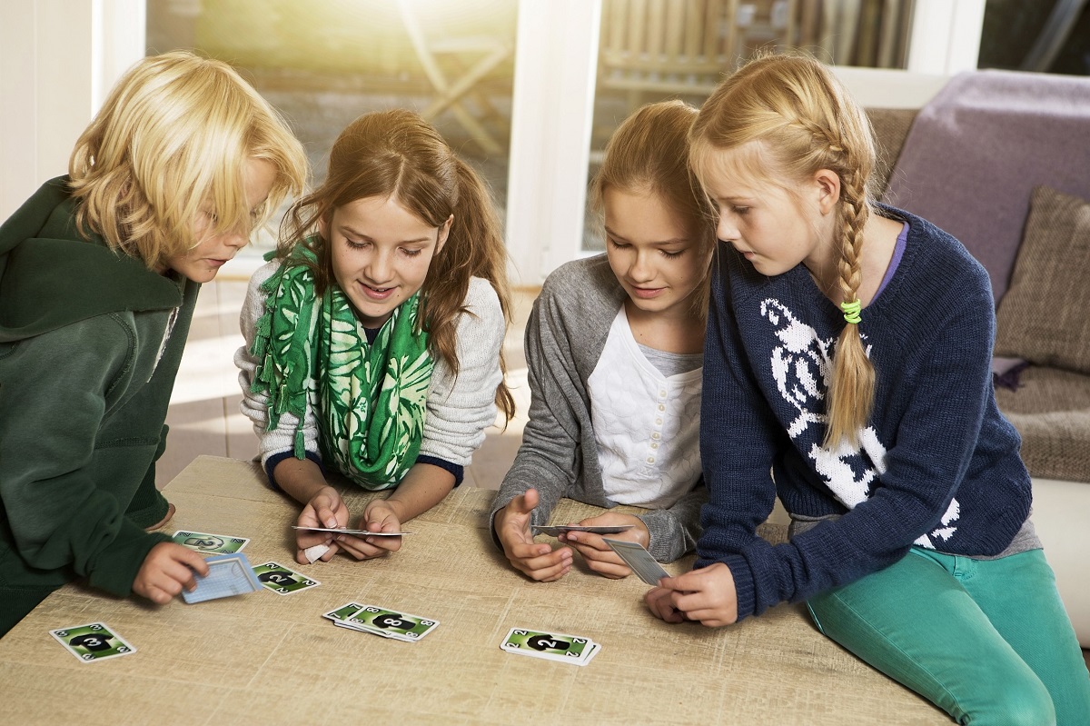 four-children-playing-card-game-in-living-room