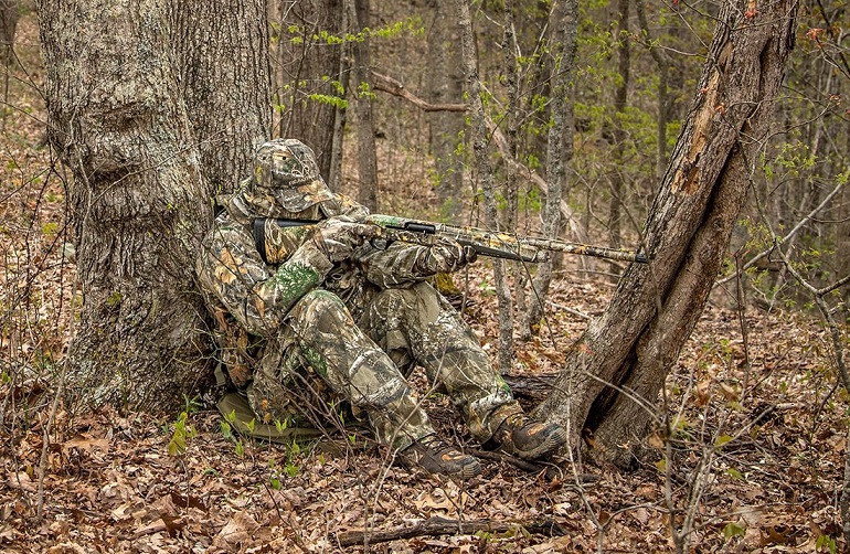Camouflaged hunter aiming with his gun