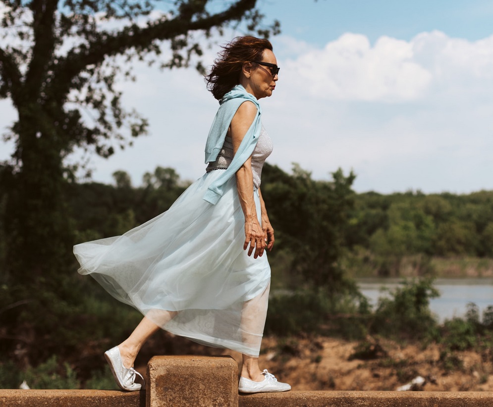picture of an active older woman wearing stylish clothes walking beside a lake