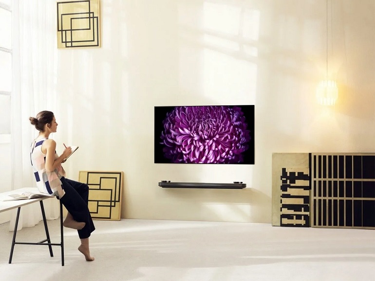 picture of a woman standing beside a amrt tv 48 inch in a big room with paper and pen in her hand 